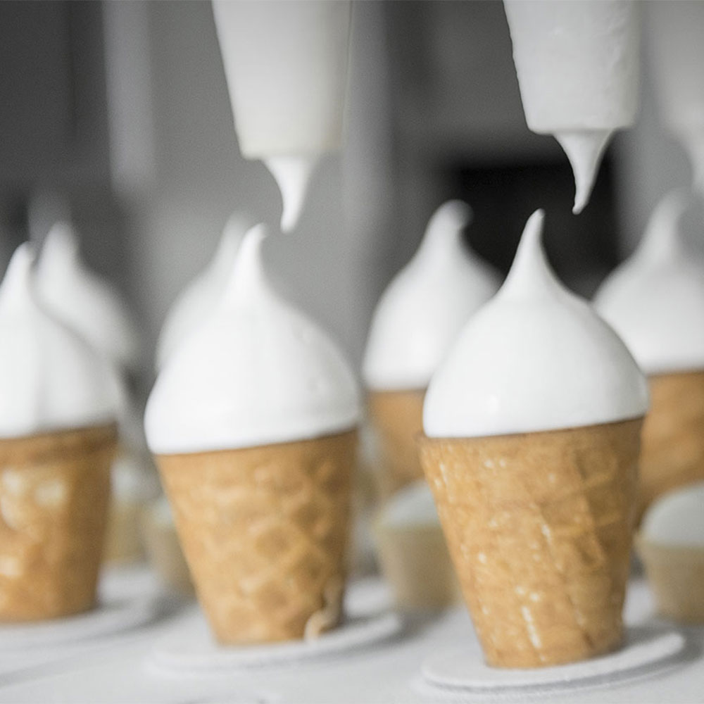 Eistüten sind in einer Vorrichtung und mit Spritzgerät wird die Eiscreme auf die Eistüte gesetzt